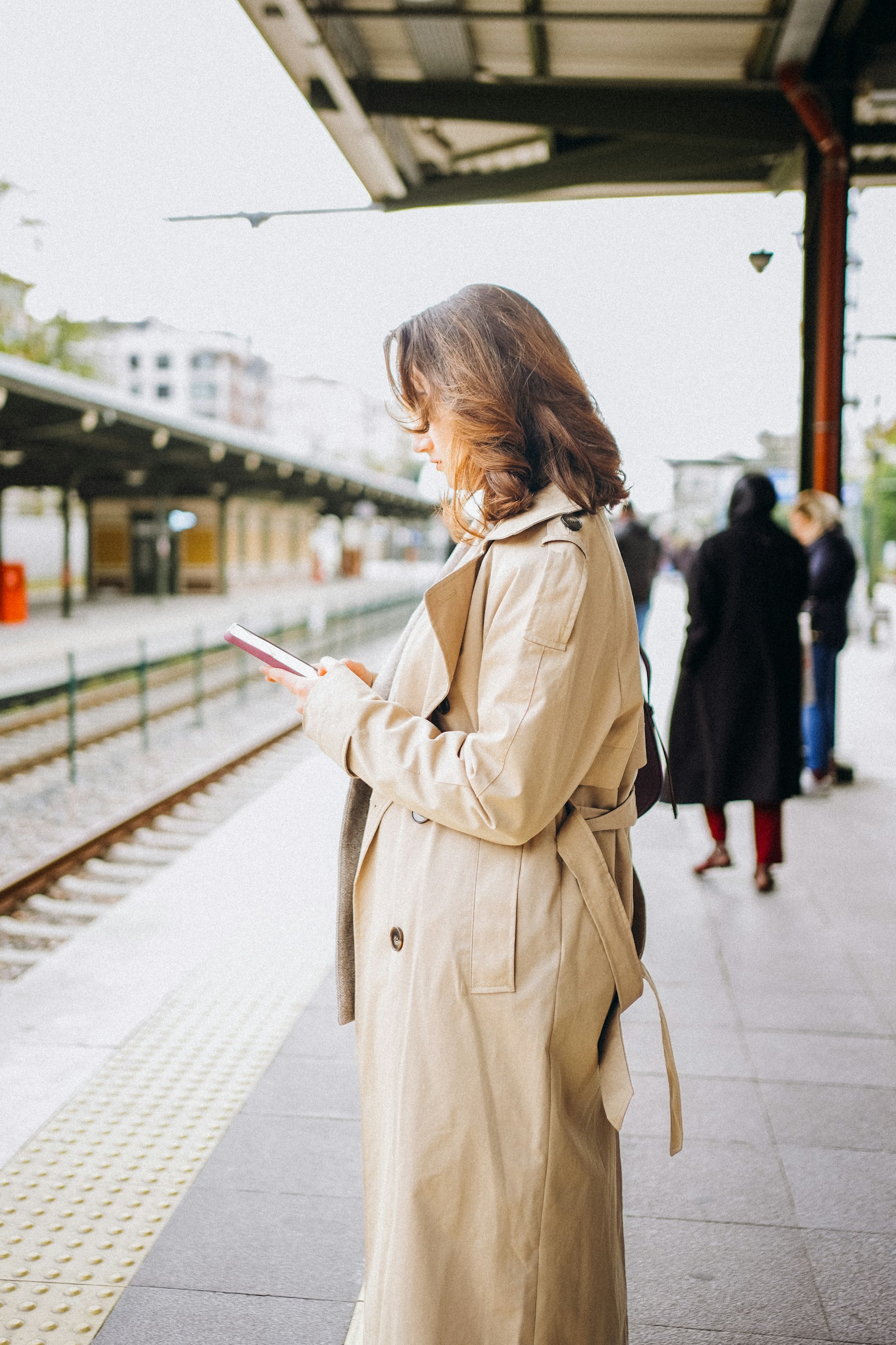 Reiziger bekijkt haar telefoon op een modern treinstation